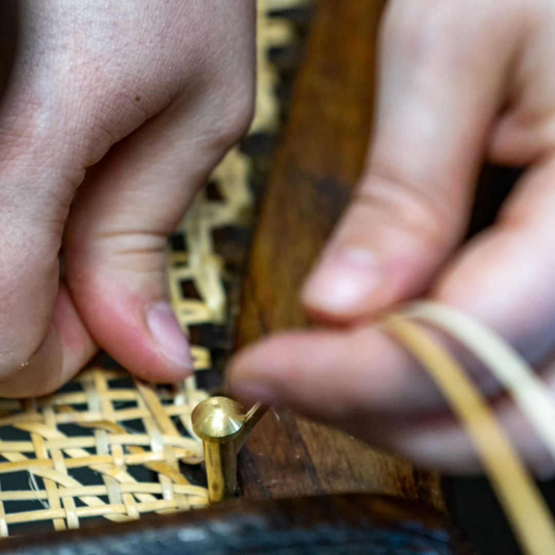 Photo des mains d'Inès Hayaud en train de tisser à la main un fauteuil en cannage